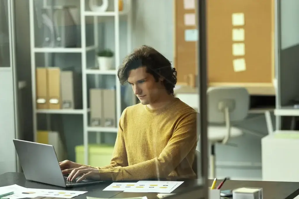 Mann arbeitet konzentriert am Laptop mit einem Sharepointtool für digitale Zusammenarbeit und Dokumentenmanagement